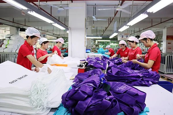 Chinese bag factory workers preparing bulk custom bag production on a work table