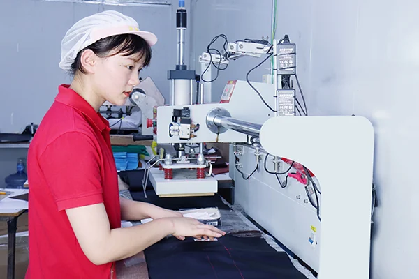Chinese bag factory worker sewing a bag panel for logo customization projects
