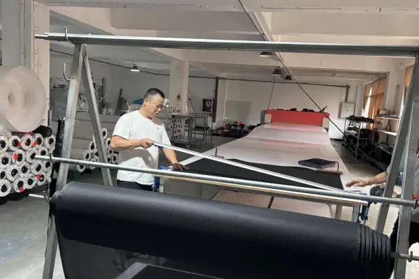 Chinese bag factory worker handling fabric roll material before cutting
